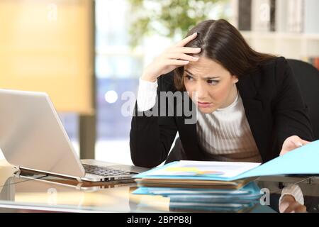 Femme d'inquiétude avec un travail difficile de regarder son portable à la ligne dans un bureau à l'office de tourisme Banque D'Images