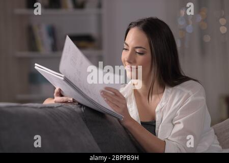 L'étude de l'étudiant à lire des notes en tournant la page assis sur un canapé dans la nuit à la maison Banque D'Images