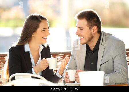 Deux cadres discutant pendant une pause-café assis sur une terrasse de bar avec un éclairage chaleureux Banque D'Images