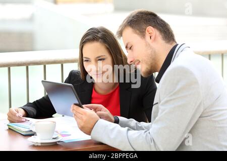 Deux cadres de consultation sur les contenus en ligne avec une tablette assis dans un café Banque D'Images