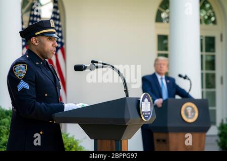 Spencer Garrett, policier de New York, prononce un discours tandis que le président Donald Trump se penche sur la cérémonie de reconnaissance présidentielle : travail acharné, héroïsme et espoir dans le jardin des roses de la Maison Blanche le 15 mai 2020 à Washington, D.C., l'événement a honoré les travailleurs de première ligne luttant contre la pandémie du coronavirus COVID-19. Banque D'Images