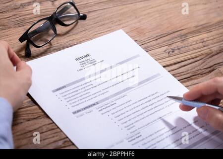 Close-up of Businessman Holding Pen in Hand Reading Résumé Sur le bureau en bois Banque D'Images