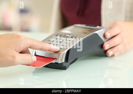 Gros plan d'un client saisissant une broche dans un lecteur de carte de crédit sur un comptoir dans un magasin Banque D'Images