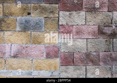 La texture de fond d'un mur fait de gros rouge, gris, jaune et blanc des briques usées. Grunge fond. Banque D'Images