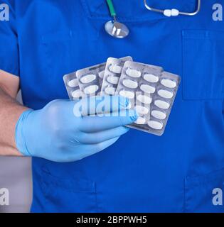 Médecin en uniforme bleu et des gants stériles holding white pills in pack Banque D'Images