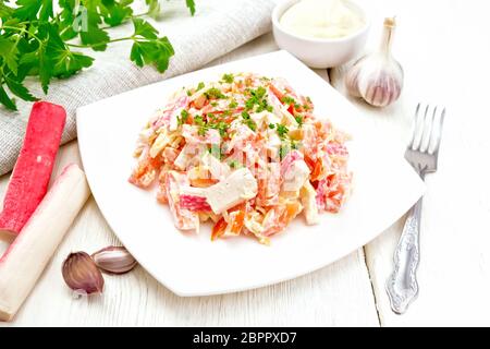 Bâtonnets de crabe salade, fromage, l'ail et les tomates, habillé avec de la mayonnaise, serviette et parsley on a wooden board background Banque D'Images