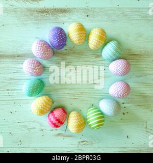 Cercle coloré d'oeufs de Pâques décoré de rayures, de fleurs et de taches en bleu, vert et jaune sur fond de bois vert avec espace de copie pour votre holi Banque D'Images