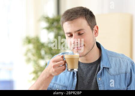 Dégustation de l'homme café avec du lait et sentir son parfum à la maison Banque D'Images