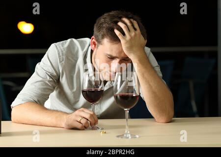 Vue de face d'un triste homme qui se plaint après une pause ou une mauvaise date dans un bar la nuit Banque D'Images