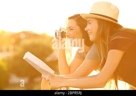 Deux touristes photographiant avec un appareil photo d'époque depuis un balcon d'hôtel au coucher du soleil Banque D'Images