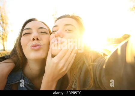 Funny friends un avec un périphérique inconnu selfies au lever du soleil avec la chaude lumière du soleil dans l'arrière-plan Banque D'Images