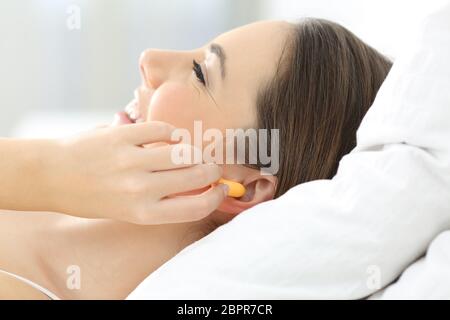 Vue latérale d'une femme part couvrant les oreilles avec des bouchons sur le lit Banque D'Images