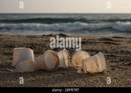 Les tasses à café sales jetables en plastique ont déchargé les déchets, jeté la pollution sur le rivage de mer Banque D'Images