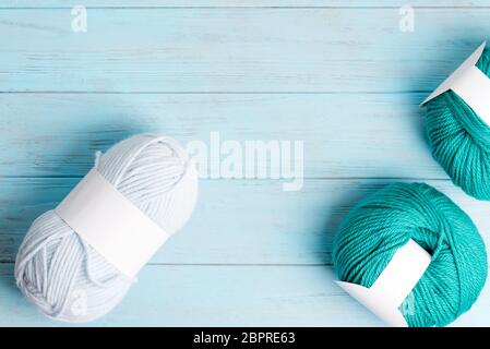 Des laines tortueuses multicolores pour tricoter et créer des objets modernes et du tissu sur un fond en bois bleu clair. Vue de dessus. Banque D'Images