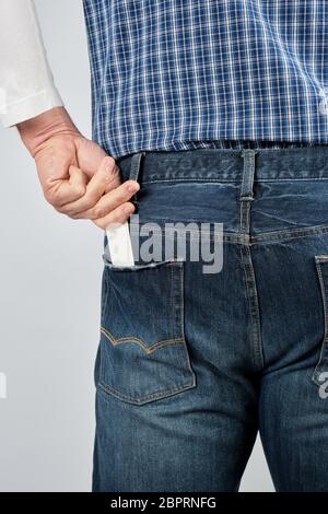 Homme met une carte papier blanc vide dans sa poche de jean arrière, Close up Banque D'Images