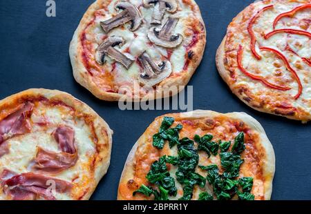 Mini pizzas divers nappages sur la planche de bois Banque D'Images