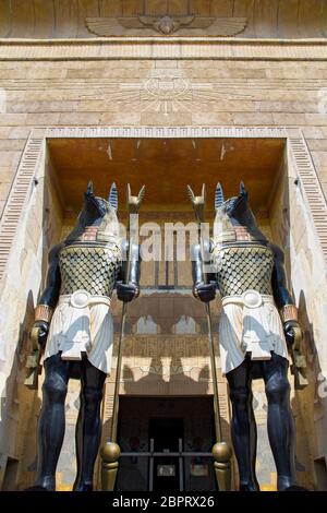 Deux statues énormes du dieu égyptien Anubis - le dieu de l'après-vie avec des matraques dans leurs mains gardent l'entrée de l'édifice. Vue de dessous. Banque D'Images