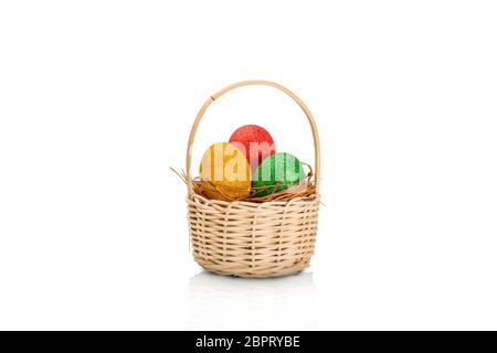 Les oeufs de Pâques colorés avec des paillettes dans le nid en bois isolé sur fond blanc sur le panier. Joyeuses Pâques Banque D'Images