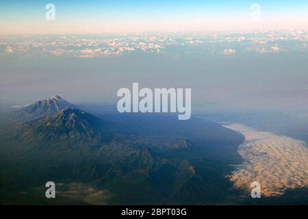 Mont Merbabu (avant) et Mont Merapi (arrière-plan). Vue aérienne depuis un vol. Photo d'archive. Province centrale de Java, Indonésie. Banque D'Images