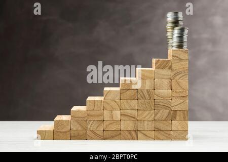 Concept de croissance. Graphique avec marches en bois sur fond gris avec pile de pièces sur le dessus. Banque D'Images