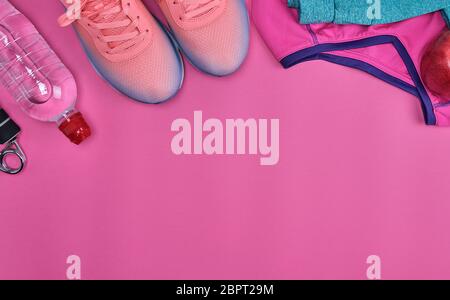 Sports rose chaussures textiles et autres éléments de la condition physique sur un fond rose, vue du dessus Banque D'Images