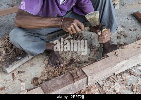 Close up d'avertir les mains de menuisier travaillant avec des outils manuels à l'atelier de menuiserie traditionnelle dans un pays du tiers monde. Manuel à forte intensité de main-d'lourd wo Banque D'Images