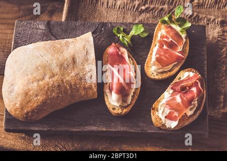 Sandwiches au fromage à la crème et au jambon sur la planche de bois Banque D'Images