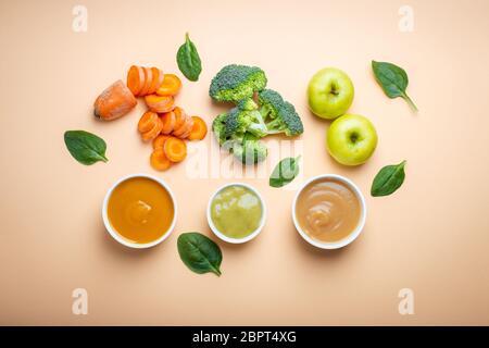 Bols blancs avec nourriture naturelle saine pour bébé sur fond pastel. Purées, faites de fruits et légumes frais biologiques, farce, vue de dessus, concept. Enfants Banque D'Images