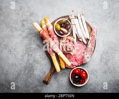 Variété de viandes froides et hors-d'œuvre, prosciutto, jambon, tranches de salami, saucisse, graissini, olives. Assortiment de viandes sur bois rustique Banque D'Images