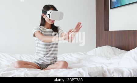 Femme regardant l'appareil de réalité virtuelle on bed Banque D'Images