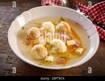 Plat de soupe de printemps de spécialité avec des boulettes de moelle et les dés de légumes frais sur une table en bois rustique avec un chiffon à carreaux Banque D'Images