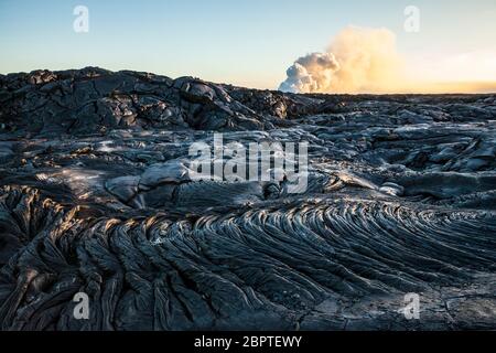 Coulées de lave et vapeur de billonnement dans la distance du point d'entrée de l'océan de lave, avril 2017, Puna, Hawaii, États-Unis. Banque D'Images