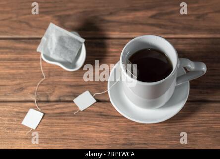 une tasse de thé avec un sac de thé sur une plaque en céramique sur une table en bois Banque D'Images