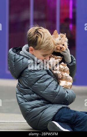 Mignon hipster garçon marche avec son drôle de terrier. Petit chien avec jeune gars passer une journée à jouer en plein air et à s'amuser. Portrait de style de vie. L'amour entre animal et propriétaire. Banque D'Images