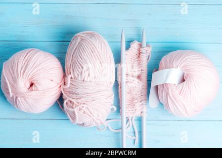 Vue de dessus des laines sinueuses et du motif à tricoter sur un fond en bois bleu clair. Banque D'Images