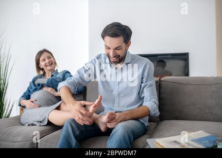 Homme aux cheveux foncés faisant un massage des pieds à sa femme enceinte Banque D'Images