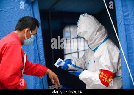 Jilin, province chinoise de Jilin. 19 mai 2020. Un travailleur communautaire vérifie la température corporelle d'un résident dans une collectivité de la zone de développement industriel de haute technologie de la ville de Jilin, dans la province de Jilin, au nord-est de la Chine, le 19 mai 2020. La province de Jilin, dans le nord-est de la Chine, a signalé quatre nouveaux cas confirmés de COVID-19 mardi, a déclaré la Commission nationale de la santé dans son rapport quotidien mercredi. Crédit: Yan Linyun/Xinhua/Alay Live News Banque D'Images