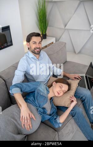 Jeune femme enceinte dans une veste de jeans se sentant fatiguée en posant sur ses genoux de mari Banque D'Images