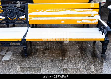 Vue de face de bancs en bois jaune sous la neige sur la place Manezhnaya dans la ville de Moscou en hiver Banque D'Images