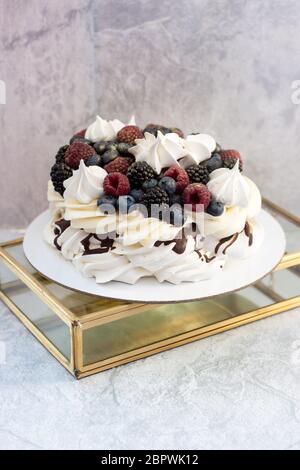 Gâteau meringue Pavlova à la framboise mûre fraîche, mûre et myrtille, et crème fouettée sur fond gris. Banque D'Images