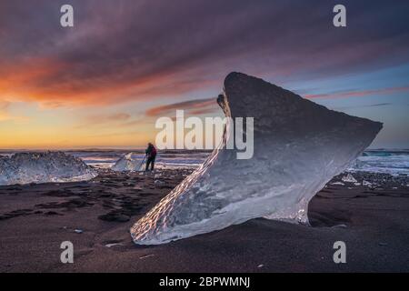 Plage de diamants, Islande du Sud - 27 février 2019 : lever du soleil sur la plage de diamants, près du glacier de Jokulsarlon, avec un photographe sur la plage Banque D'Images