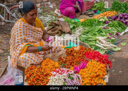 Varanasi, Inde - 13 novembre 2015. Une femme indienne veuve se trouve sur le côté d'une rue, vendant des fleurs fraîches pour des offrandes hindoues pendant Diwali. Banque D'Images