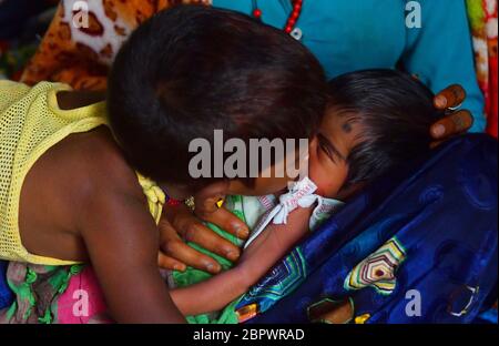 AGARTALA,TRIPURA,INDE,28-04-2020 : Manju Bauri, mère de 23 ans, qui est un travail migré, du Rajasthan, travaillant à Agartala, son fils aîné joue avec son nouveau-né, Qui a pris naissance le 13 avril, au soir 5 , lors d'un confinement national imposé par le gouvernement comme mesure préventive contre le COVID-19, à Agartala, capitale de l'État de Tripura, au nord-est de l'Inde. Le gouvernement tripura a déplacé 33 000 Rajasthanin ont migré du travail dans une école, qui s'est bloquée en raison de ce coup de serruck, à Agartala. Banque D'Images