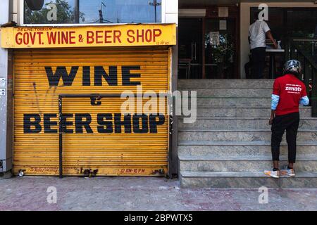 Zomato Guy se tenant à côté d'un magasin de vins et spiritueux fermé pour la collecte de nourriture qui a été fermé après de grandes foules, alors que l'Inde reste sous un verrouillage étendu sans précédent sur le coronavirus hautement contagieux (COVID-19) le 04 mai 2020 à New Delhi, Inde. Dans le cadre des relaxations annoncées par le gouvernement indien au cours de la troisième phase de l'isolement national du coronavirus, les magasins autonomes peuvent fonctionner en assurant la mise en œuvre de la distanciation sociale et la présence d'au plus cinq personnes à la fois. Photographe : Kuldeep Singh Rohilla Banque D'Images