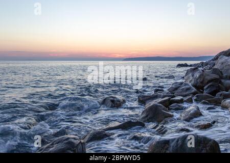 La vague de la mer frappe les pierres au coucher du soleil près de la côte du Saint Mont Athos Banque D'Images