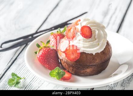 Rum baba décoré de crème fouettée et de fraises fraîches Banque D'Images