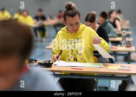 Ravensburg, Allemagne. 20 mai 2020. Un élève regarde les missions pendant l'examen final allemand dans la salle de sport de l'Albert-Einstein-Gymnasium; sur son sweat-shirt à capuche il est écrit: 'Corona HABI - resté à la maison, toujours l'a obtenu. Environ 80 étudiants suivent l'examen allemand au Albert-Einstein-Gymnasium. Credit: Felix Kästle/dpa/Alay Live News Banque D'Images