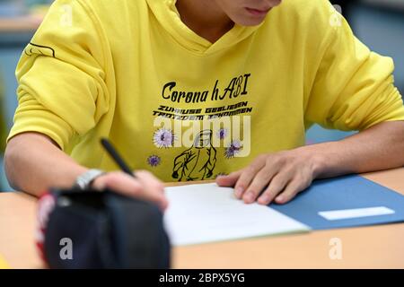 Ravensburg, Allemagne. 20 mai 2020. Un élève regarde les missions pendant l'examen final allemand dans la salle de sport de l'Albert-Einstein-Gymnasium; sur son sweat-shirt à capuche il est écrit: 'Corona HABI - resté à la maison, toujours l'a obtenu. Environ 80 étudiants suivent l'examen allemand au Albert-Einstein-Gymnasium. Credit: Felix Kästle/dpa/Alay Live News Banque D'Images