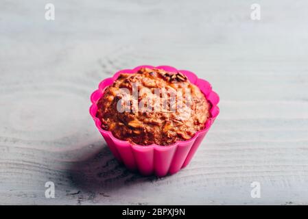 Gruau cuit dans un moule à muffins en silicone rose sur fond de cuisson en bois clair. Banque D'Images
