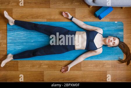 Jeune femme se détendant dans la posture du rashasana. Pratiquer le pilates et le yoga à la maison Banque D'Images